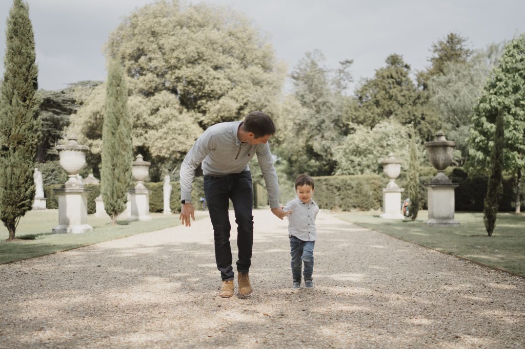 west london family photographer taking image of father running with son in chiswick house