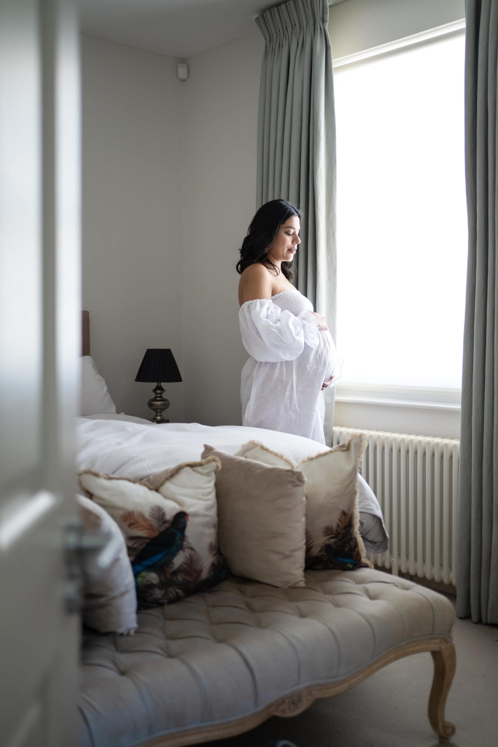 photo of pregnant woman standing by window taken by london maternity photographer