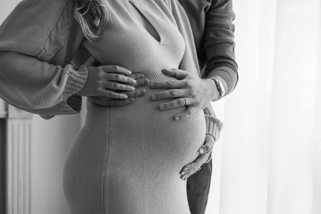 london maternity photography showing black and white image of pregnant woman and her partner cradling her pregnant belly