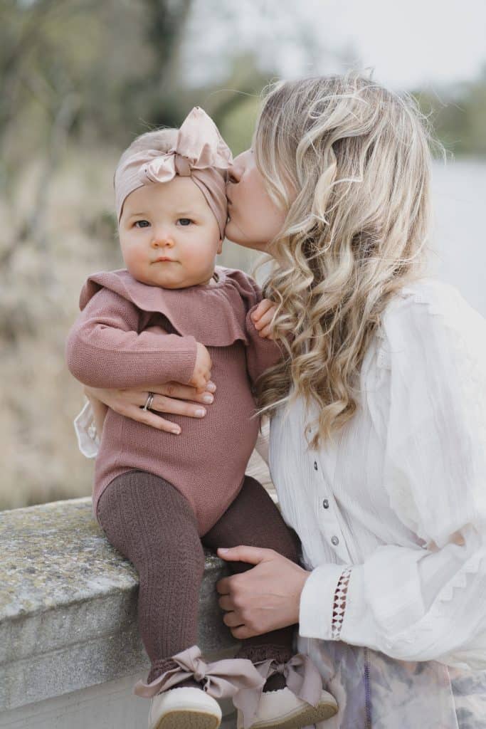 mother kissing baby girl on head